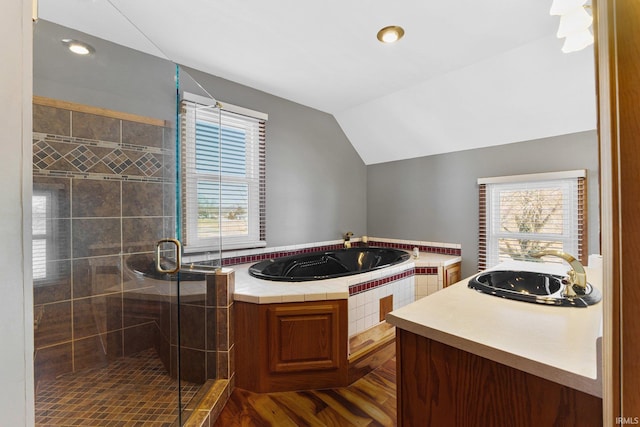 full bathroom featuring lofted ceiling, a garden tub, wood finished floors, vanity, and a stall shower