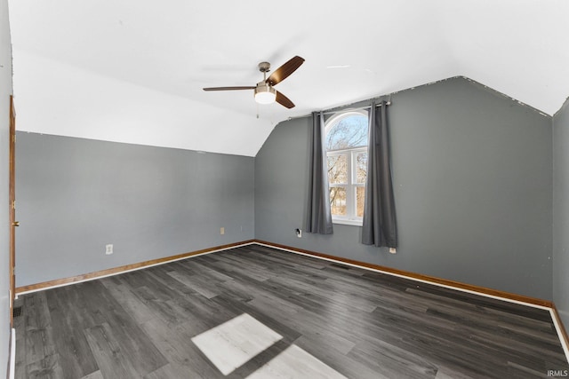 additional living space featuring dark wood-style floors, vaulted ceiling, and baseboards