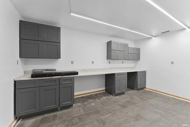 kitchen with baseboards, gray cabinets, and light countertops