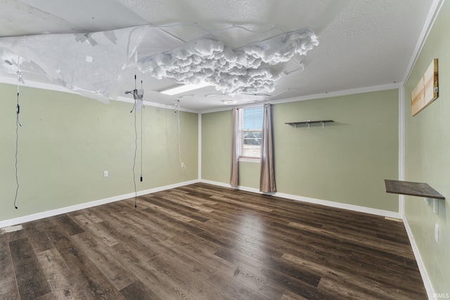 empty room with crown molding, a textured ceiling, baseboards, and wood finished floors