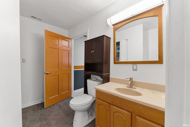 bathroom with a textured ceiling, toilet, vanity, and visible vents