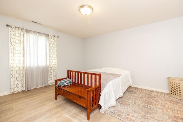 bedroom featuring light wood finished floors, visible vents, and baseboards