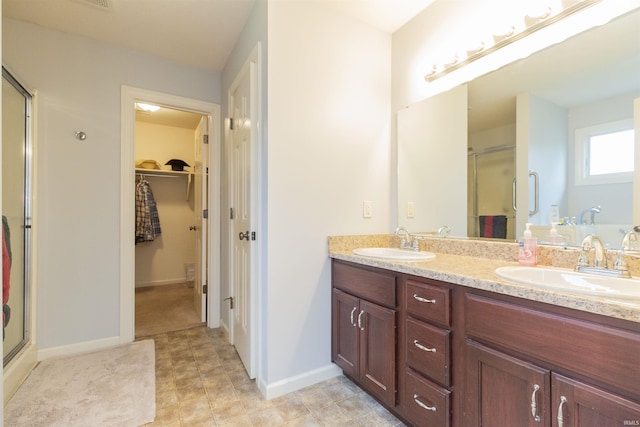 bathroom with a spacious closet, double vanity, a stall shower, and a sink