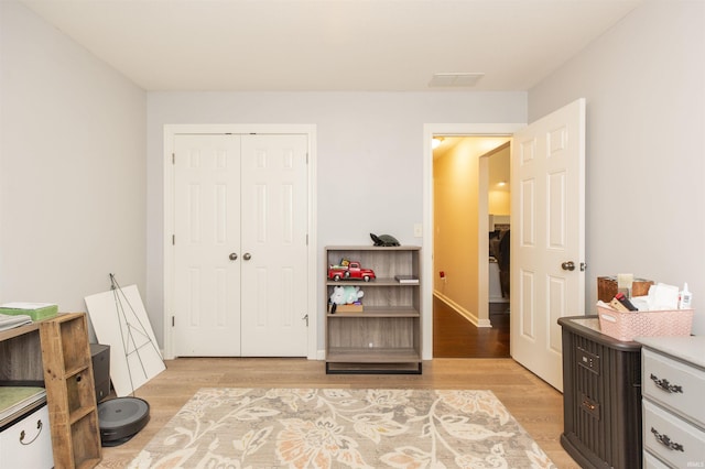 bedroom with light wood finished floors, a closet, visible vents, and baseboards