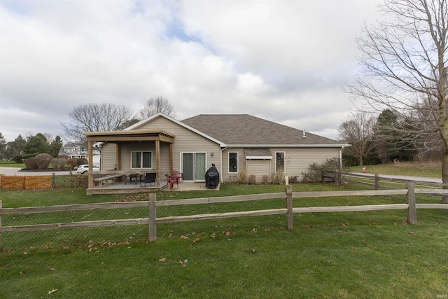 view of front of house with a patio, a front lawn, a shingled roof, and fence