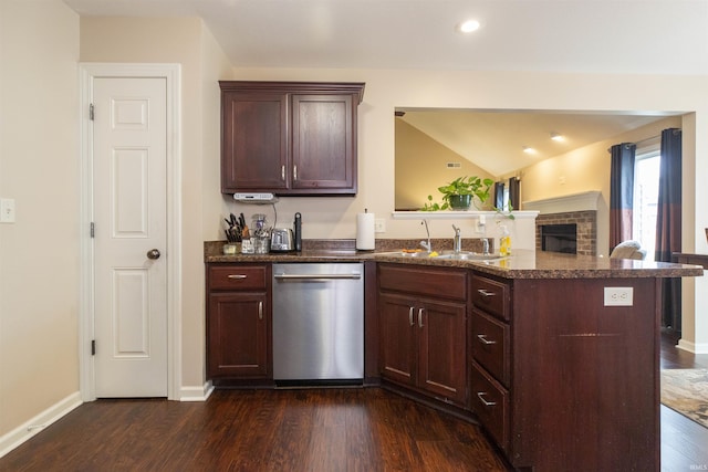 kitchen with a sink, baseboards, stainless steel dishwasher, a brick fireplace, and dark wood-style floors