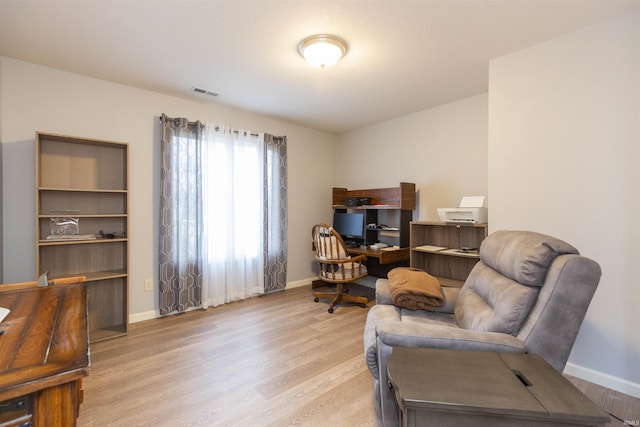 living area with light wood-style flooring, visible vents, and baseboards