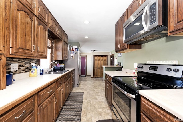 kitchen with recessed lighting, stainless steel appliances, a sink, light countertops, and decorative backsplash