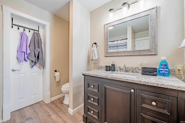 full bath with toilet, wood finished floors, vanity, and baseboards