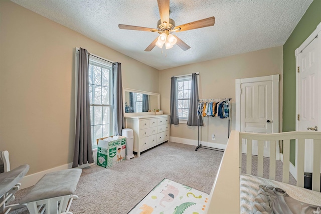 bedroom with a textured ceiling, ceiling fan, baseboards, and light colored carpet