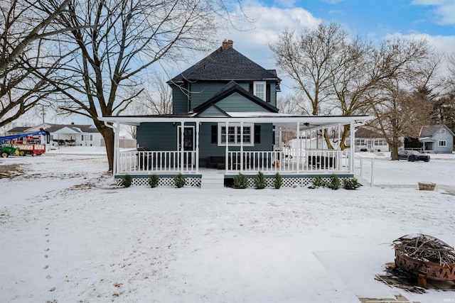 view of front facade with covered porch, an outdoor fire pit, and a chimney