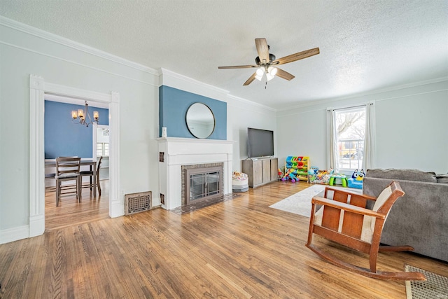 living room featuring a fireplace with flush hearth, a textured ceiling, wood finished floors, and visible vents