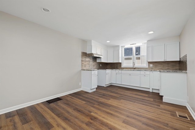 kitchen with baseboards, visible vents, white cabinetry, and backsplash