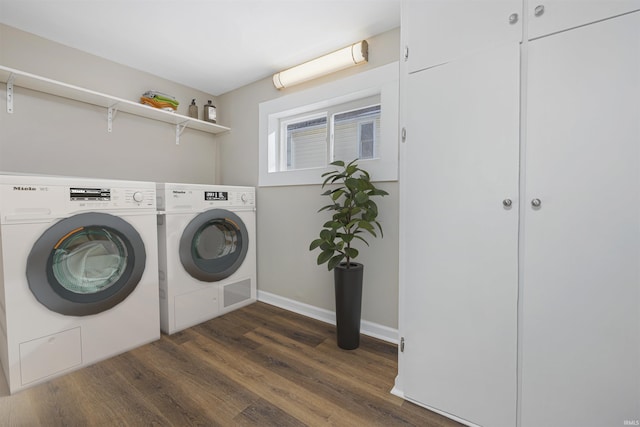 laundry room with laundry area, baseboards, dark wood-type flooring, and washing machine and clothes dryer