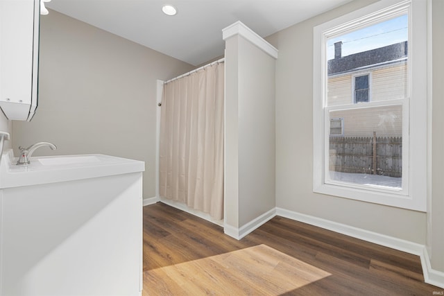 bathroom featuring a sink, baseboards, wood finished floors, and recessed lighting