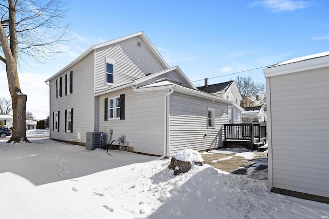 snow covered back of property with central AC