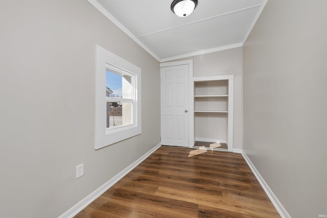 interior space featuring dark wood-style flooring, crown molding, and baseboards