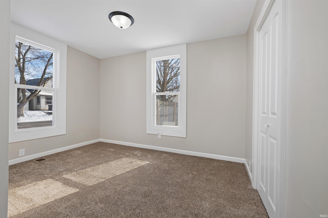 unfurnished room with a healthy amount of sunlight, baseboards, visible vents, and carpet flooring