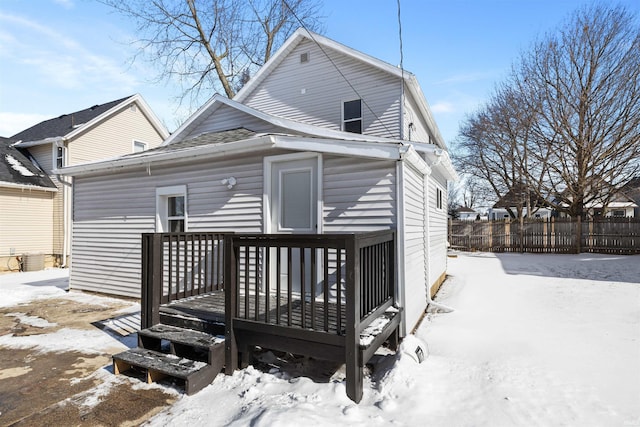 snow covered house featuring fence