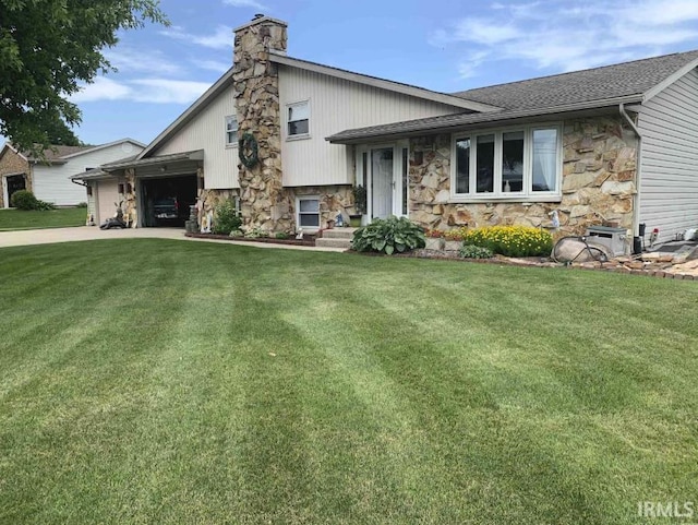 split level home featuring driveway, stone siding, a chimney, an attached garage, and a front yard