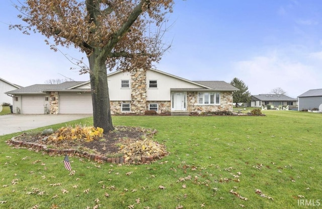 split level home featuring a garage, a front yard, stone siding, and driveway