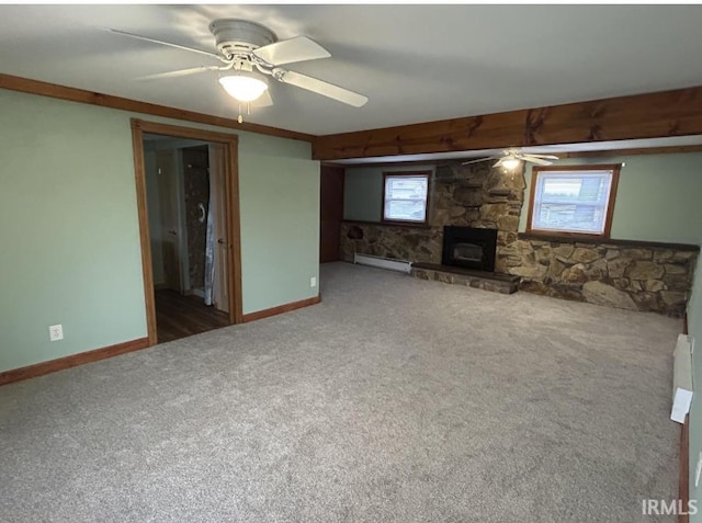 unfurnished living room with baseboards, a ceiling fan, carpet, a stone fireplace, and a baseboard heating unit