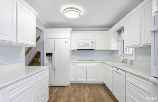 kitchen with white appliances, white cabinetry, a sink, and wood finished floors