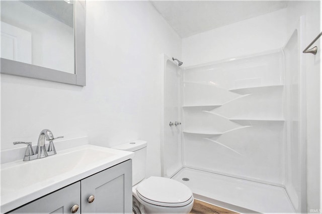 bathroom featuring toilet, a stall shower, wood finished floors, and vanity