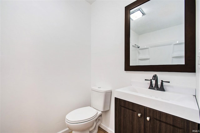 bathroom featuring toilet, baseboards, and vanity