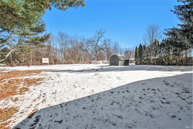 yard layered in snow with a garage, a shed, and an outdoor structure