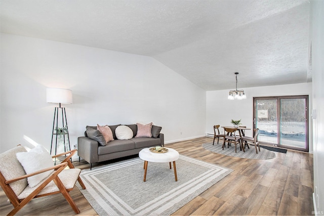 living area featuring lofted ceiling, a textured ceiling, wood finished floors, and a notable chandelier