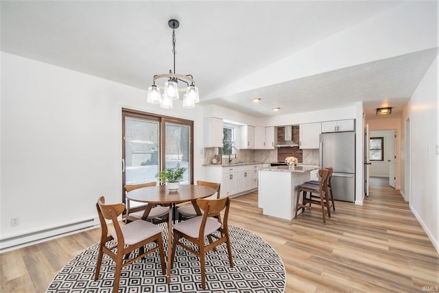 dining area featuring a baseboard heating unit, light wood-type flooring, baseboards, and an inviting chandelier