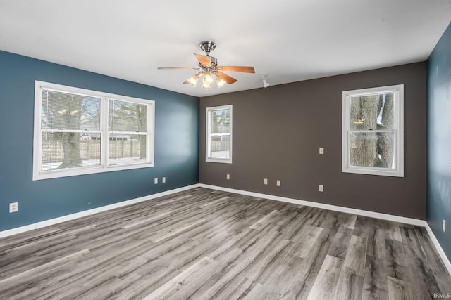 unfurnished room with light wood finished floors, baseboards, and a ceiling fan