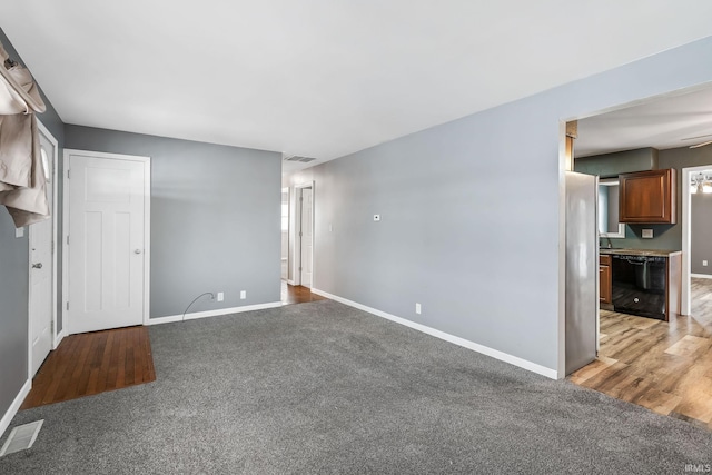 unfurnished living room featuring visible vents, light colored carpet, and baseboards