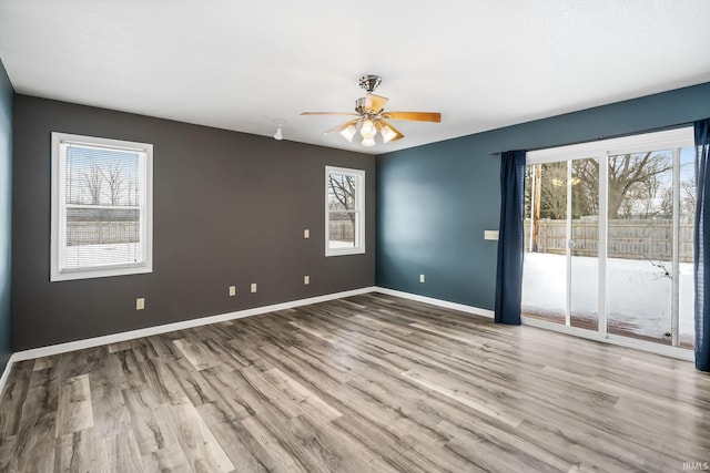 empty room featuring ceiling fan, baseboards, and wood finished floors