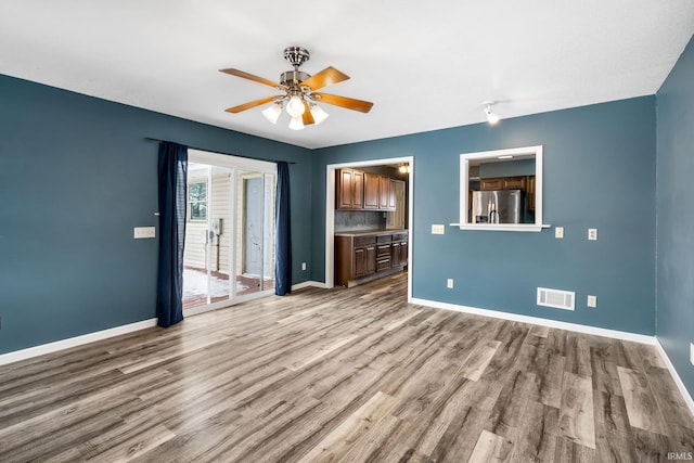 empty room featuring light wood-type flooring, baseboards, visible vents, and ceiling fan