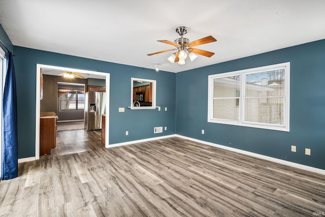 empty room featuring ceiling fan, baseboards, and wood finished floors