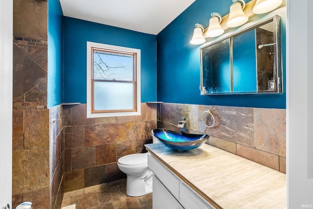 bathroom featuring tile walls, wainscoting, vanity, and toilet