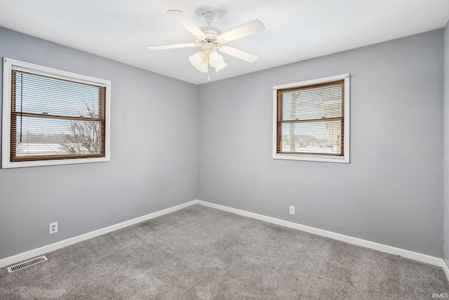 empty room featuring a ceiling fan, baseboards, visible vents, and carpet flooring