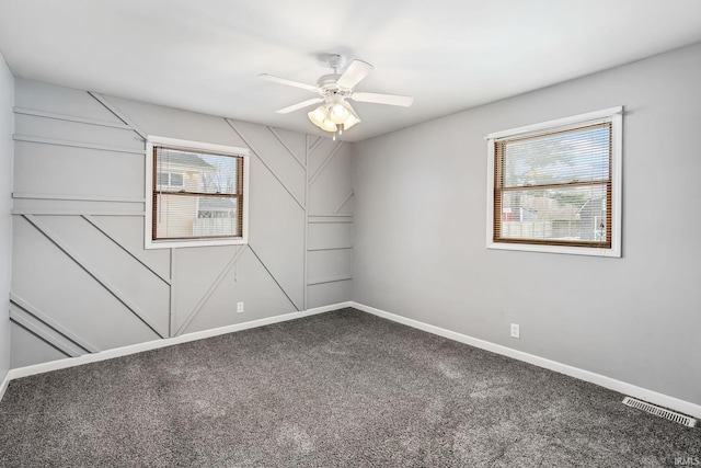 carpeted spare room with a healthy amount of sunlight, baseboards, visible vents, and a ceiling fan