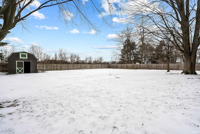 yard covered in snow featuring a shed, a detached garage, fence, and an outdoor structure