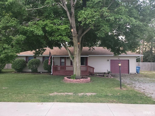 ranch-style home featuring a garage, a front yard, driveway, and fence