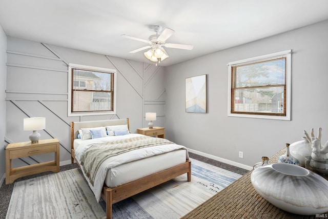 carpeted bedroom with ceiling fan, multiple windows, and baseboards