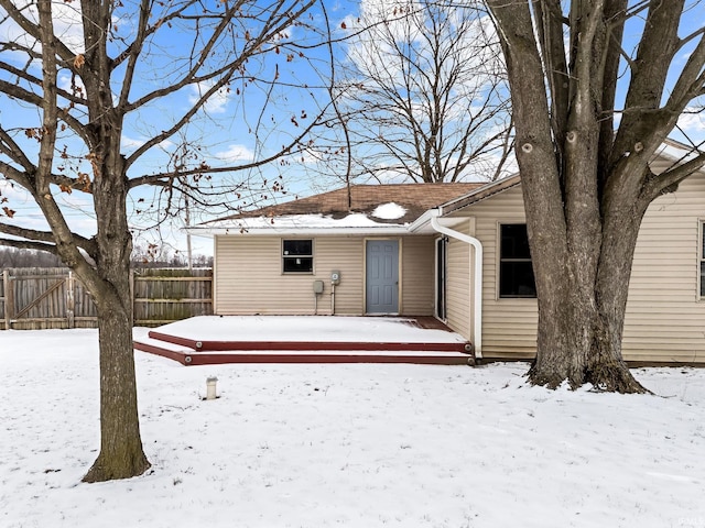 snow covered back of property with fence and a deck