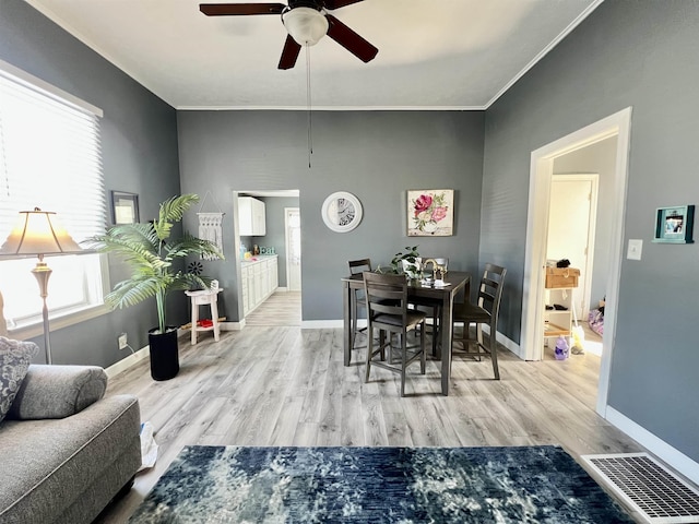 dining area featuring light wood-style floors, baseboards, visible vents, and crown molding