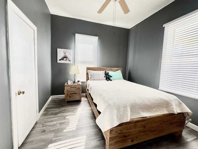 bedroom with light wood-style floors, baseboards, and a ceiling fan