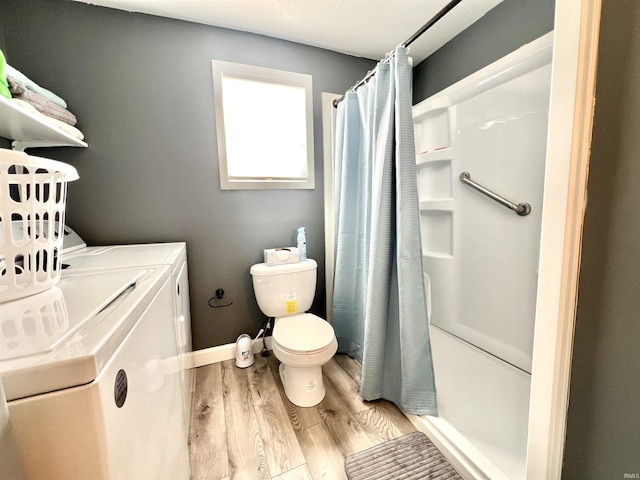 bathroom featuring curtained shower, toilet, washing machine and dryer, wood finished floors, and baseboards