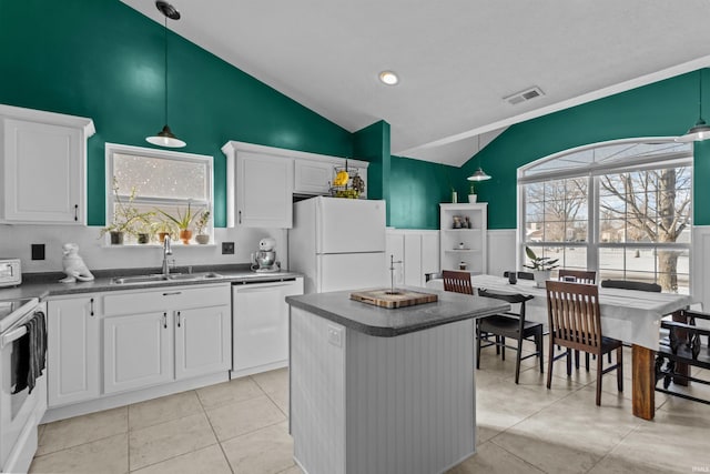 kitchen featuring white appliances, white cabinets, dark countertops, a center island, and a sink