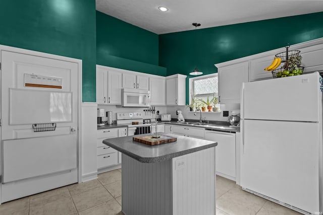 kitchen with pendant lighting, dark countertops, white cabinetry, a sink, and white appliances