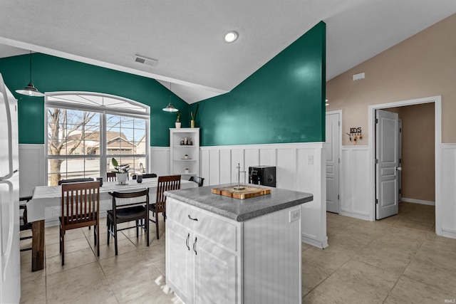 kitchen featuring dark countertops, white cabinetry, vaulted ceiling, and a center island